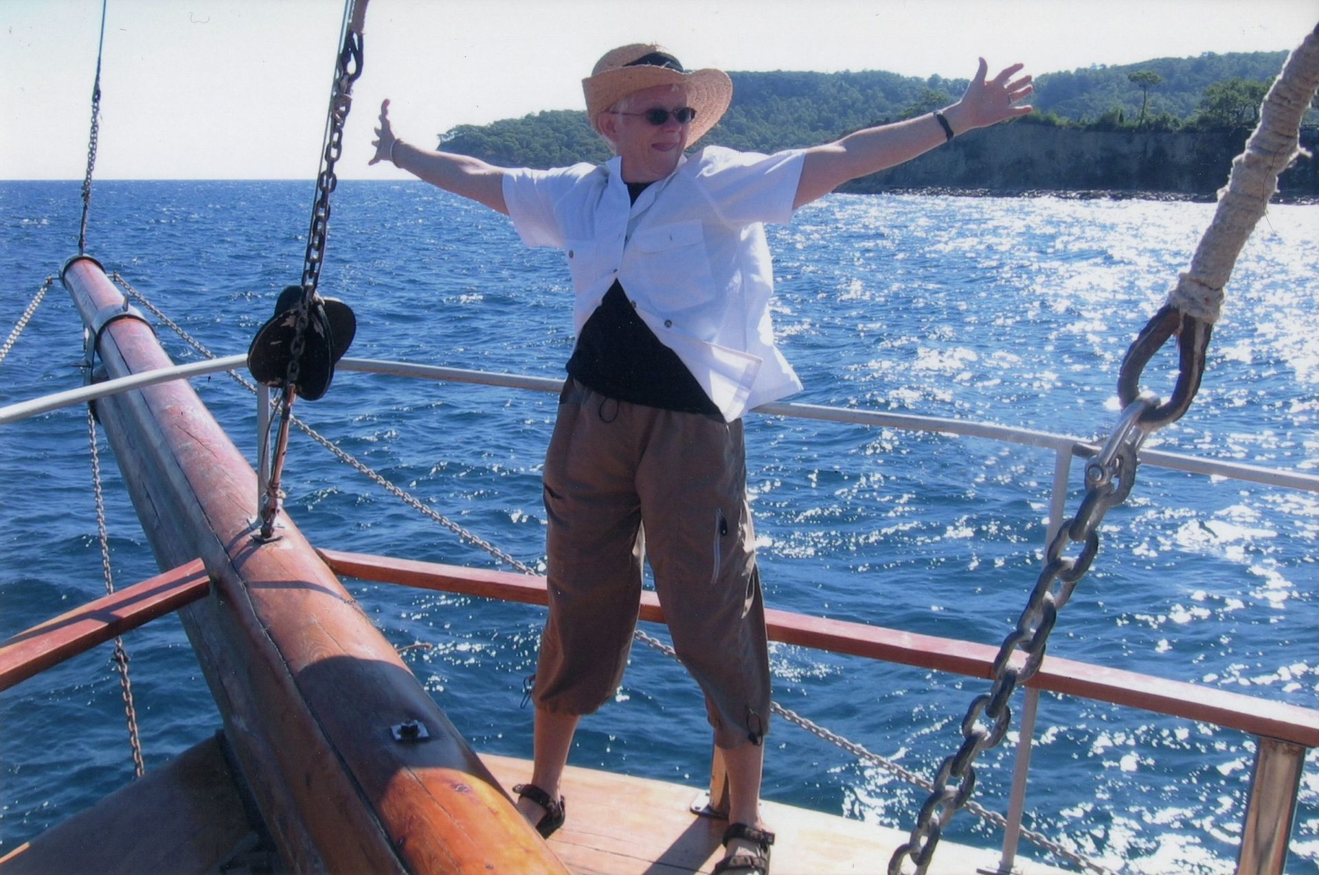 A woman is standing on a boat with her arms outstretched