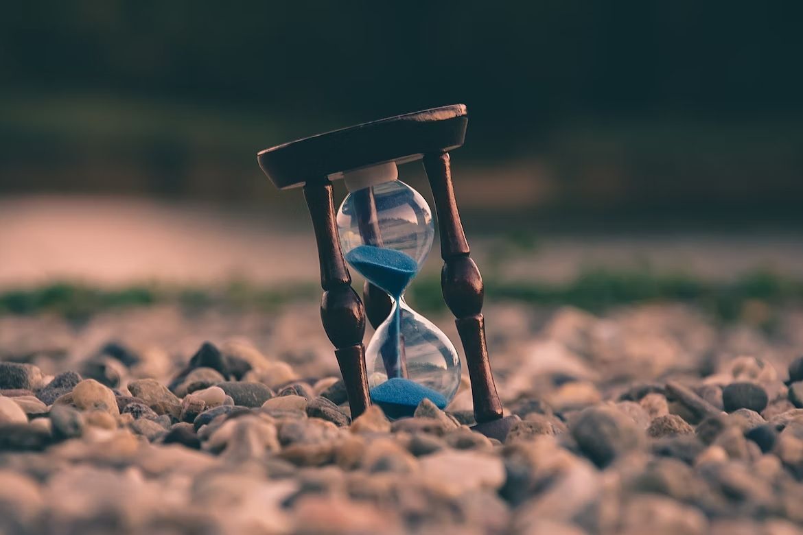 An hourglass is sitting on top of a pile of rocks.