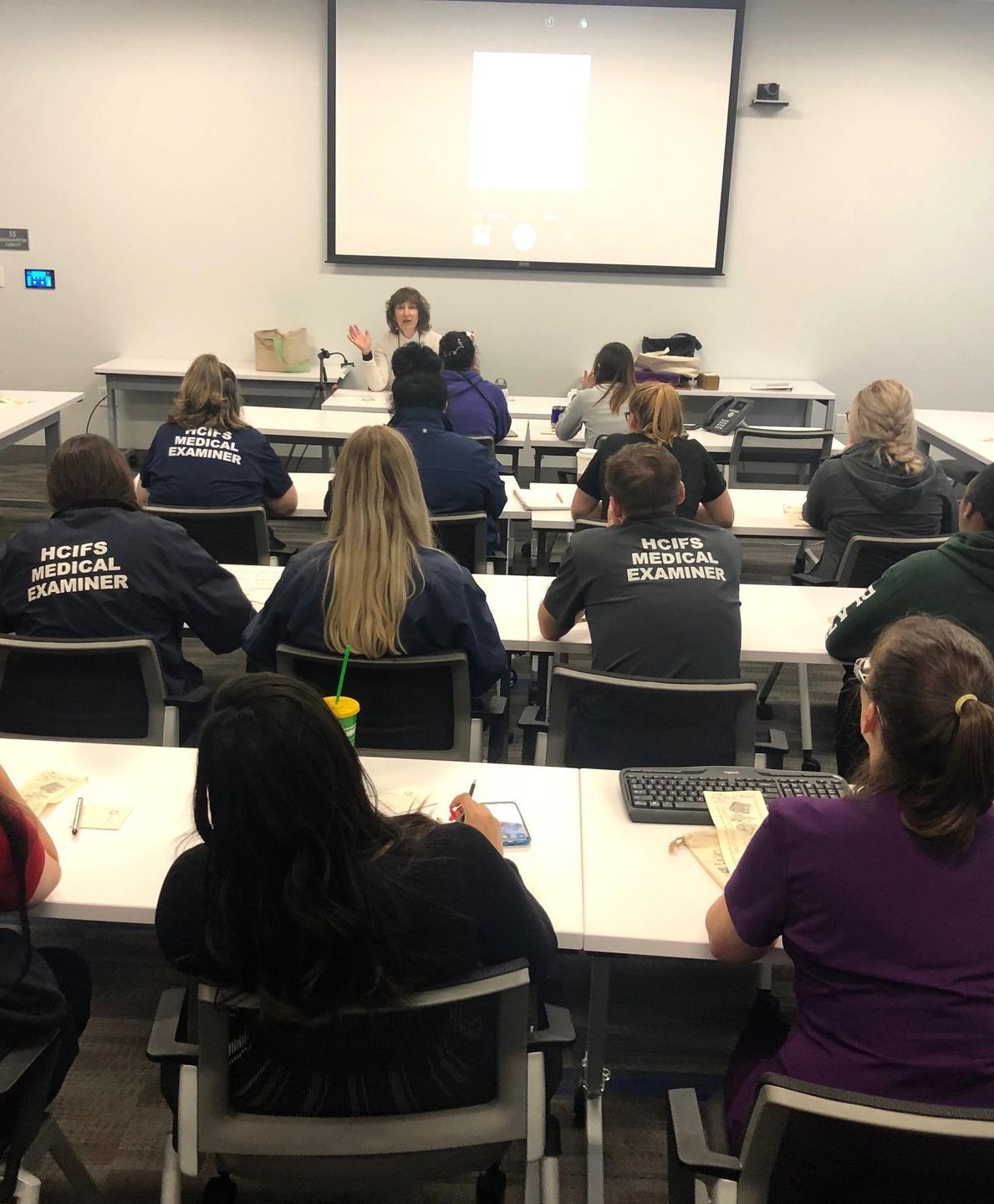 A group of people are sitting in a classroom wearing shirts that say police officers