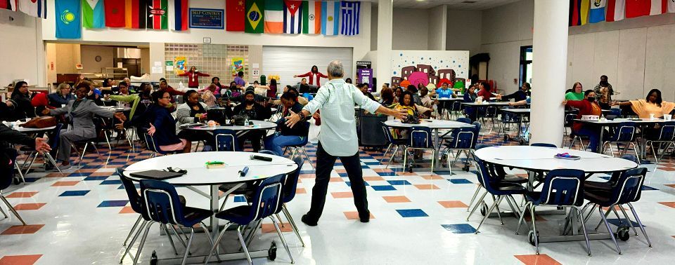 A man is dancing in a large room with tables and chairs.