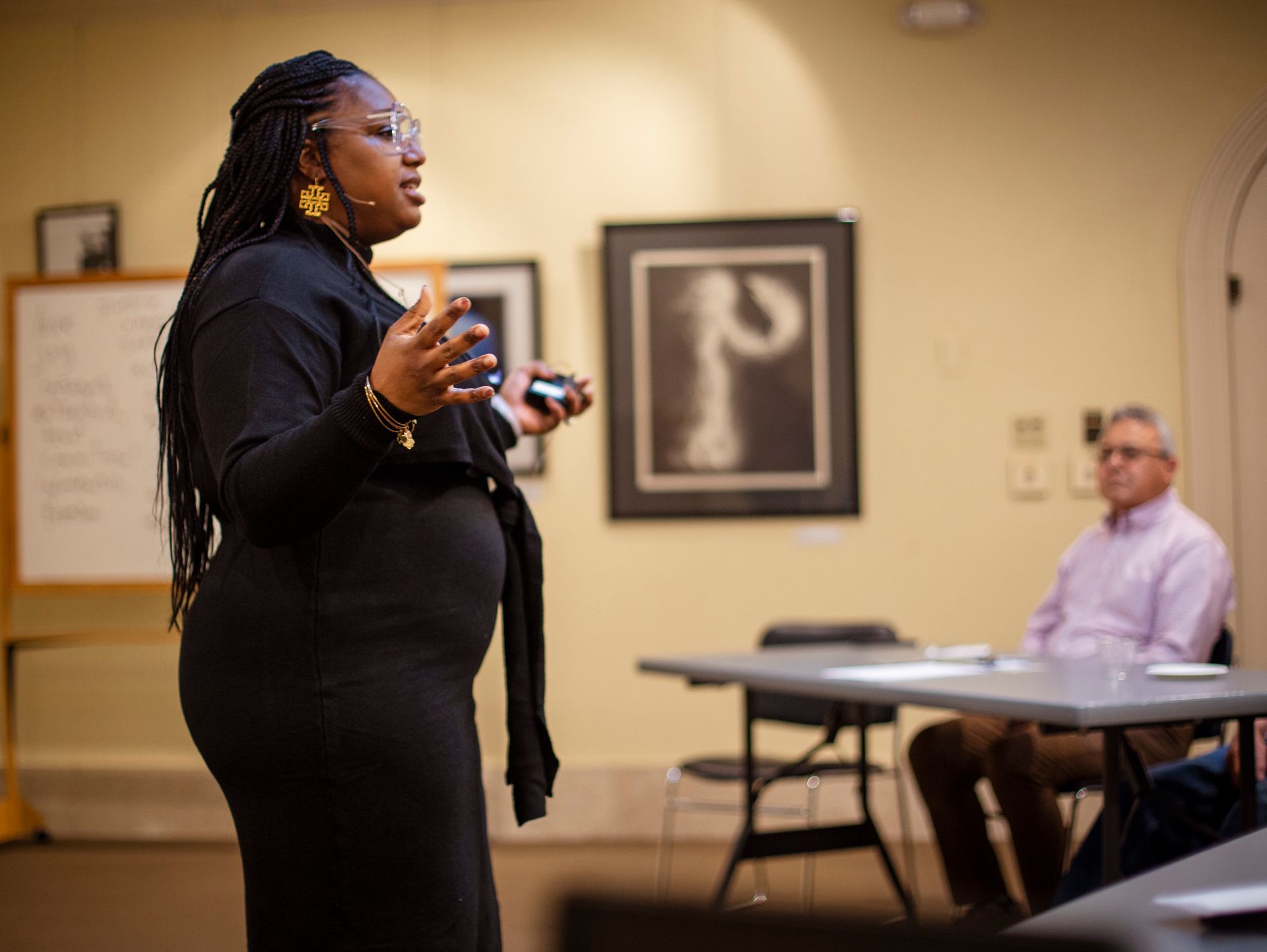 A woman is giving a presentation in front of a group of people in a room.