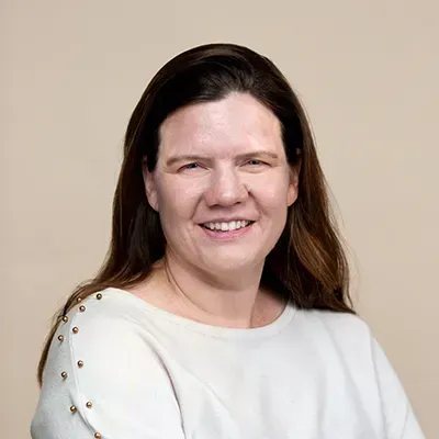 A woman in a white shirt is smiling for the camera.