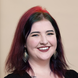 A woman with red hair and earrings is smiling for the camera.