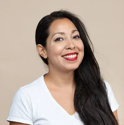 A woman with long hair and red lipstick is smiling for the camera.