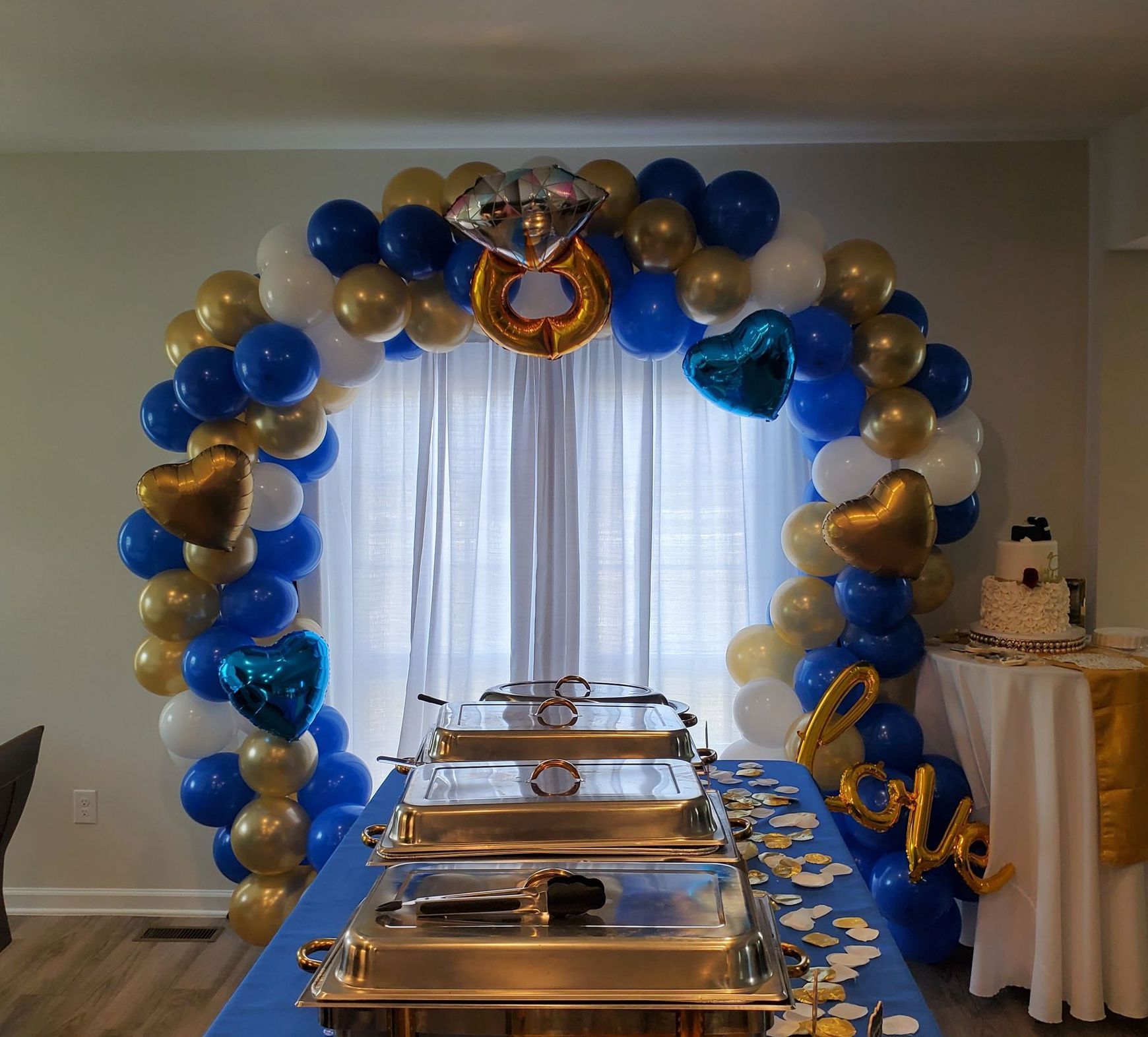 Blue and gold balloon arch over food buffet, engagement party.