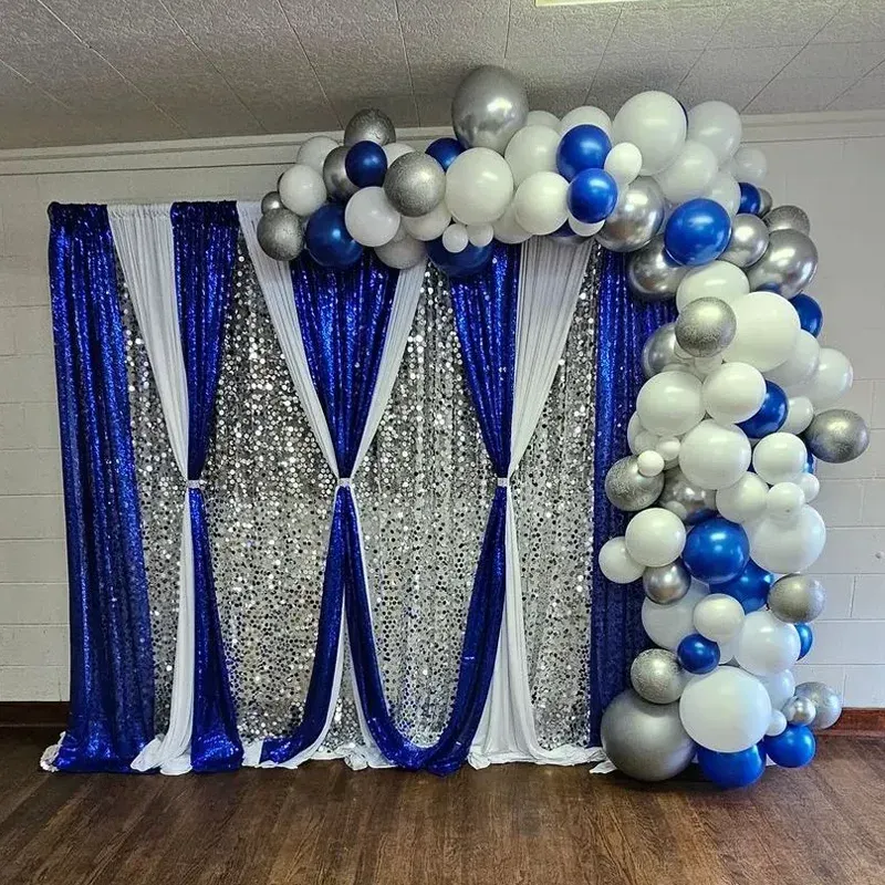Blue, silver, and white balloon arch and backdrop at event.
