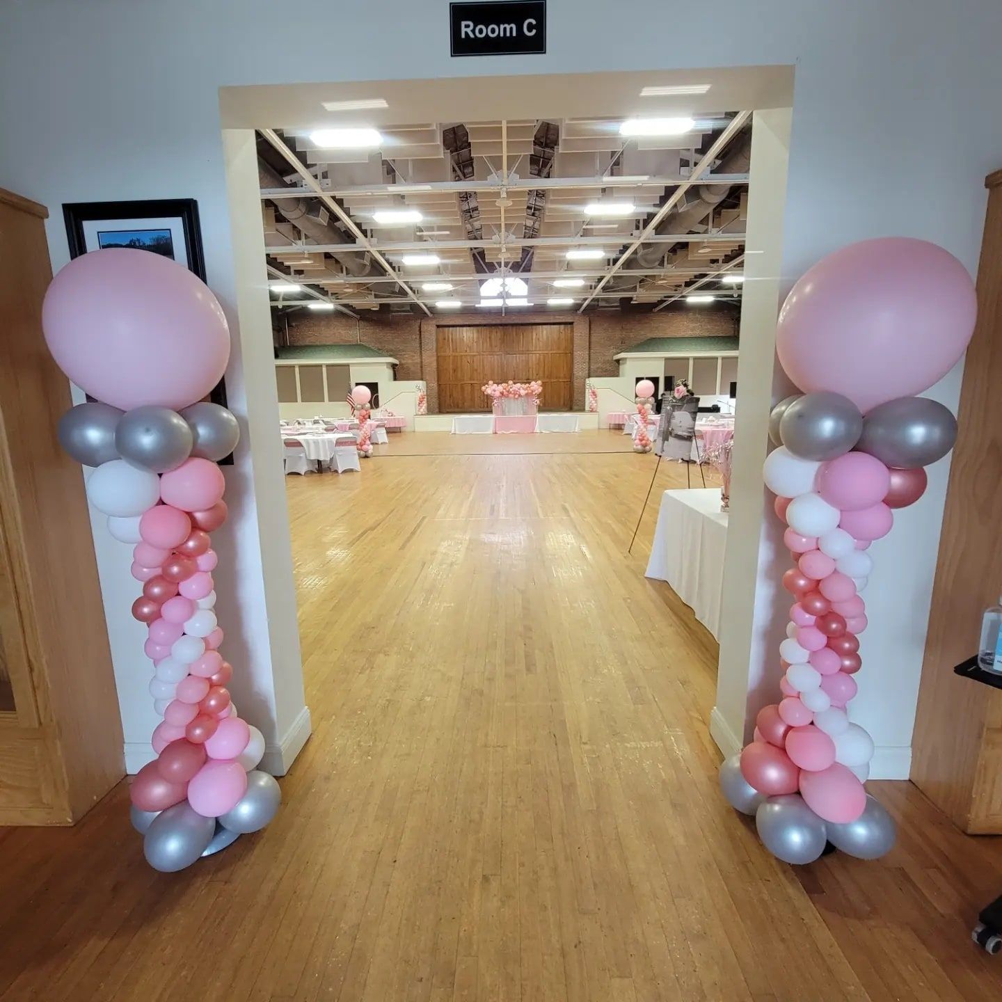 Two pink balloon columns framing a room entrance, decorated for an event.