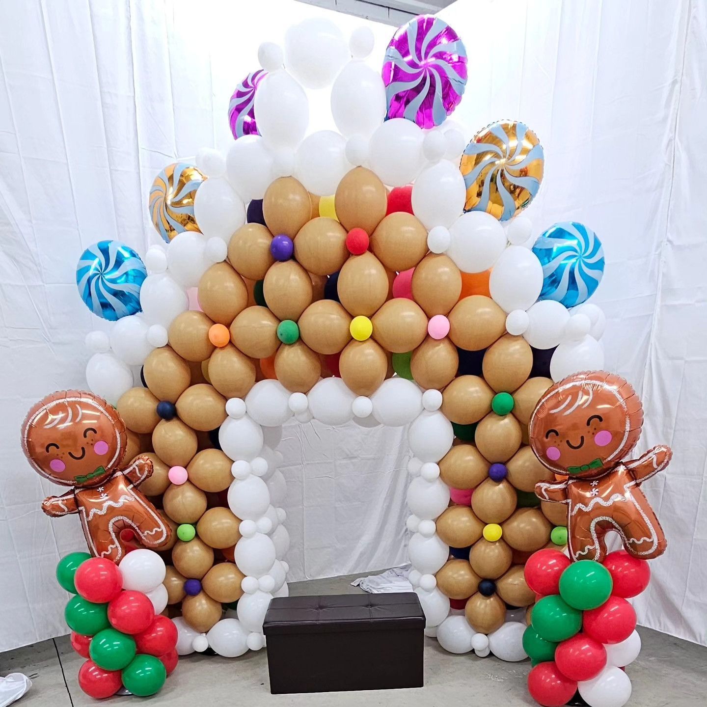 Gingerbread house arch made of balloons, with gingerbread man balloons on either side.