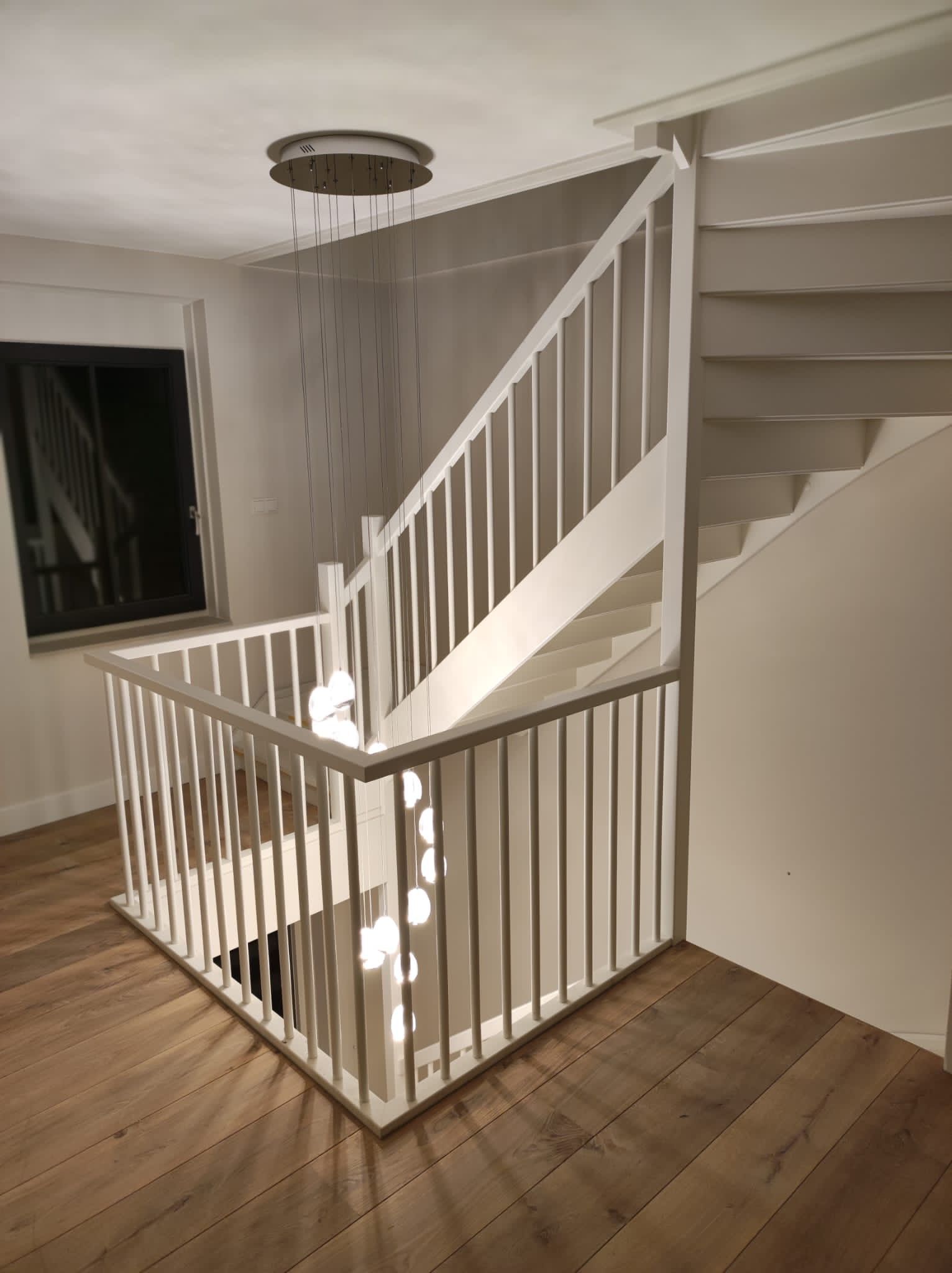 Een witte trap met een houten balustrade in een kamer met een houten vloer.
