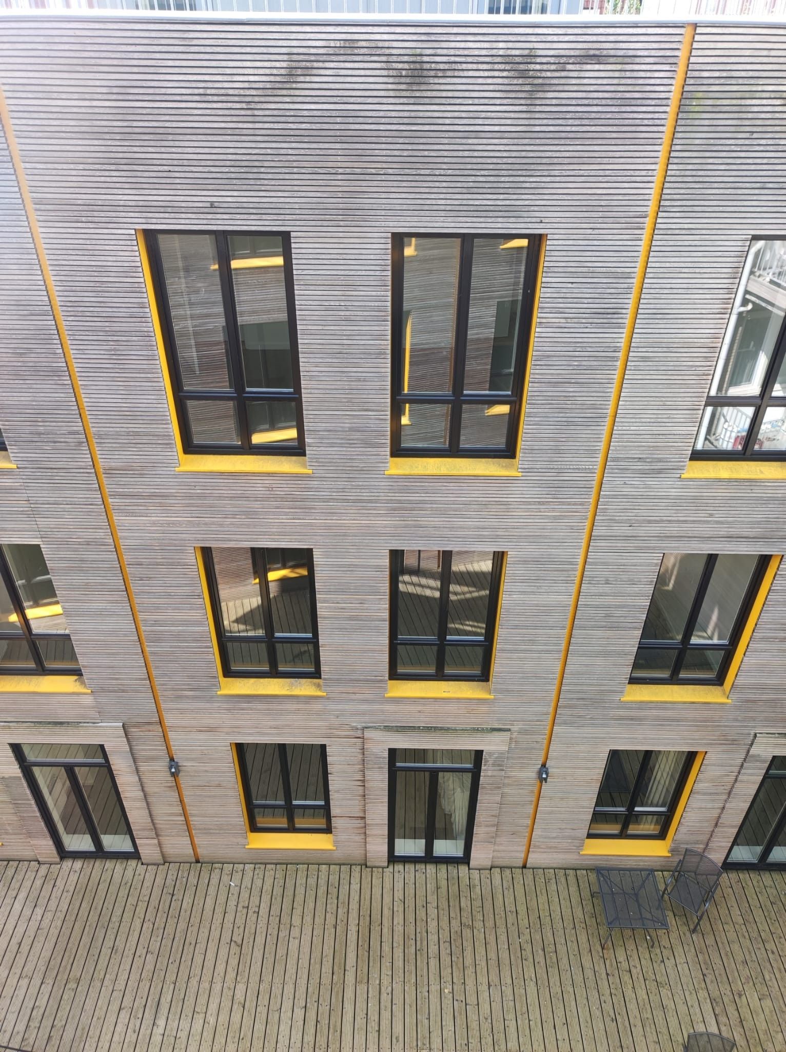 Een luchtfoto van een gebouw met veel ramen en gele bekleding.