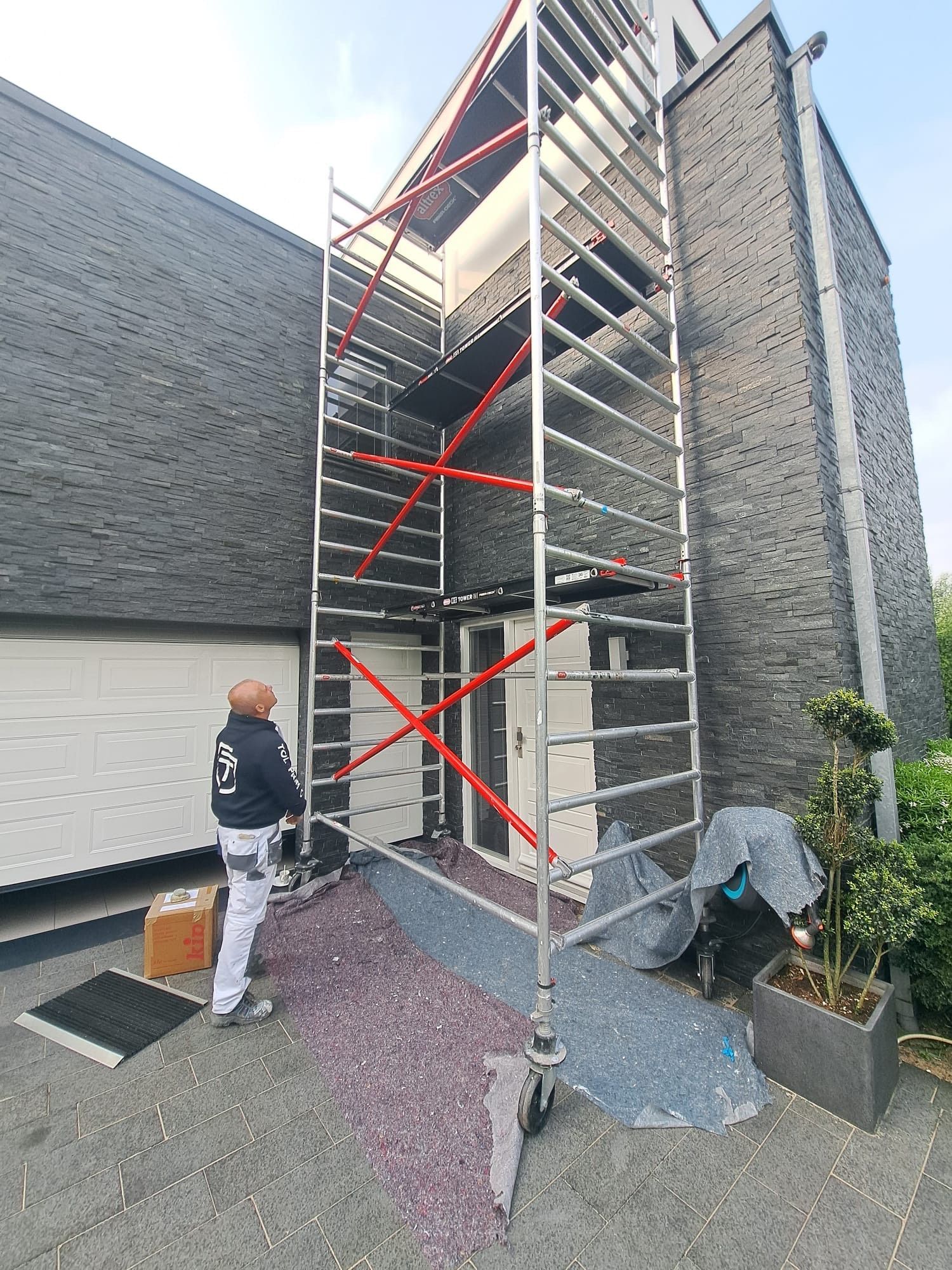 Een man staat naast een steiger voor een gebouw.