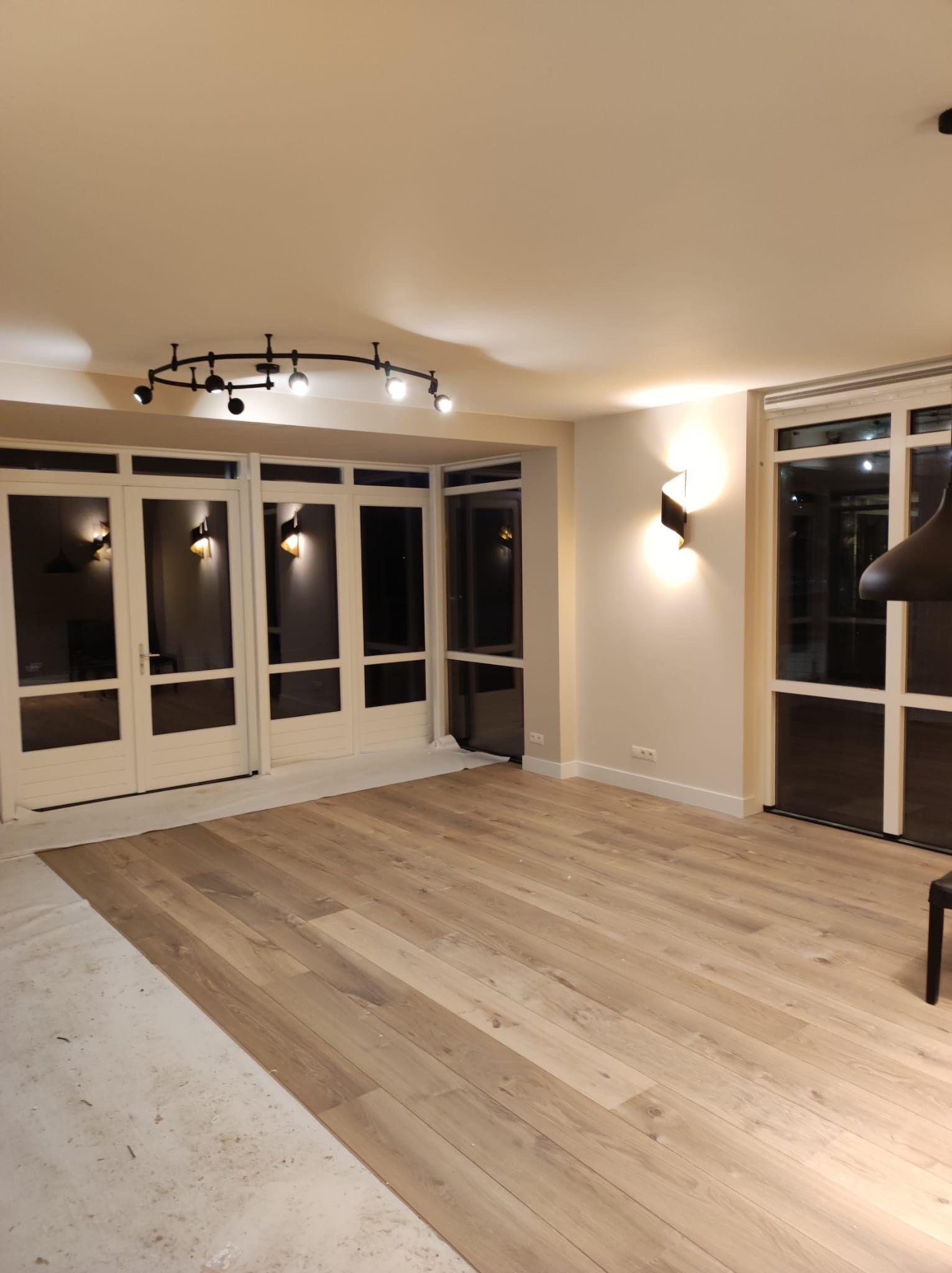 Een lege woonkamer met hardhouten vloeren en een open haard.