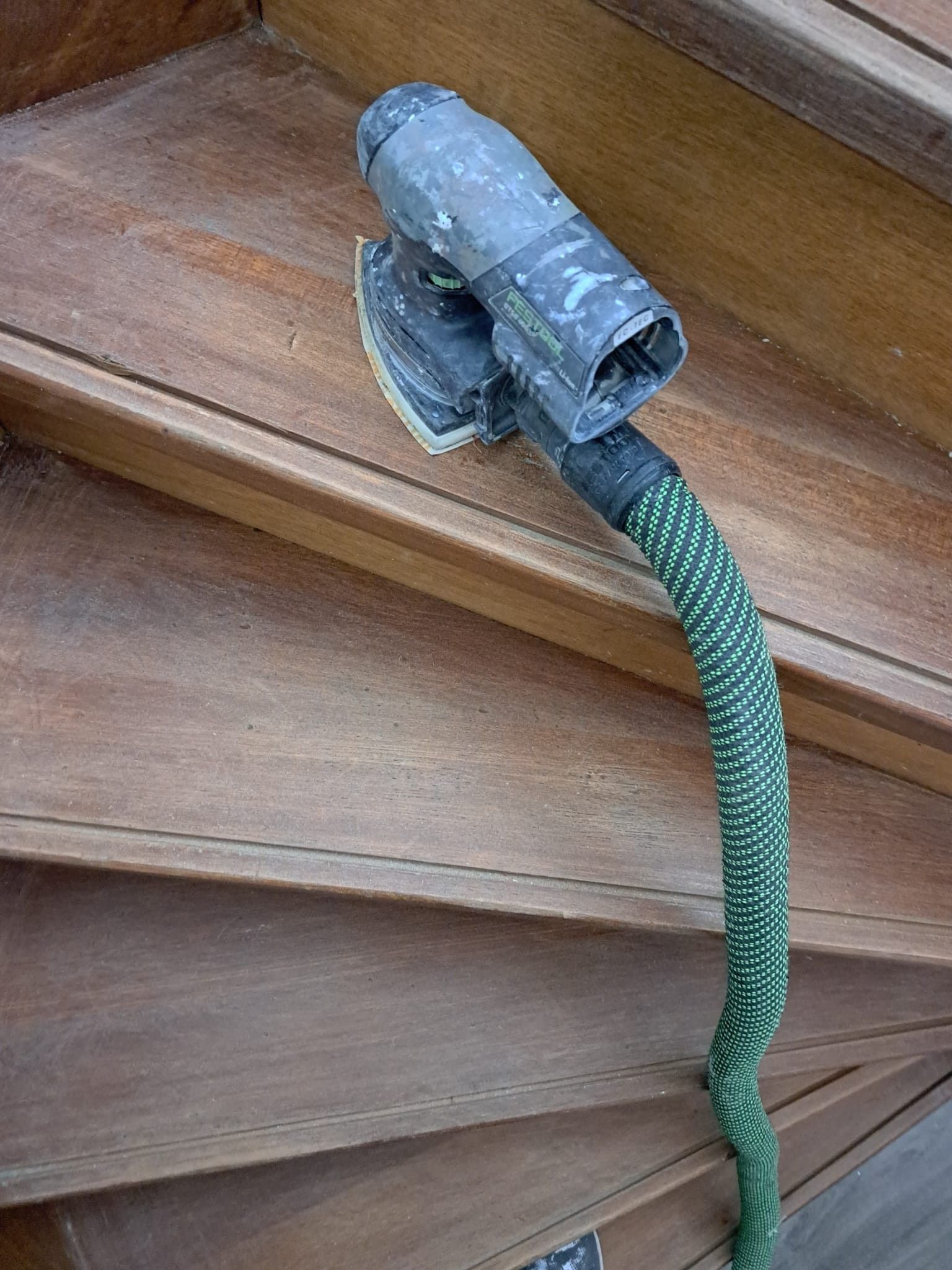 Een houten trap met een groene slang eraan