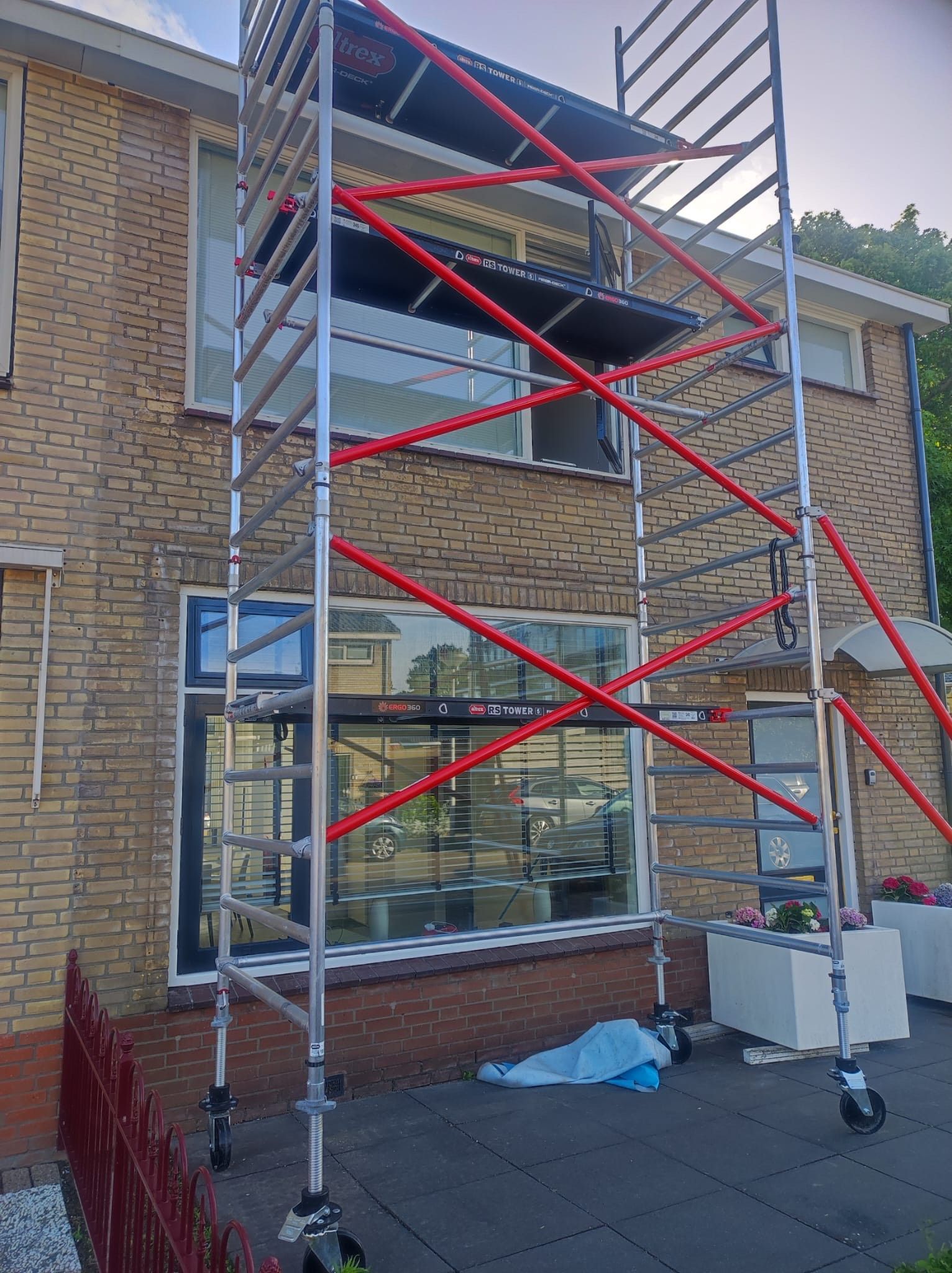 Voor een bakstenen gebouw staat een steiger.