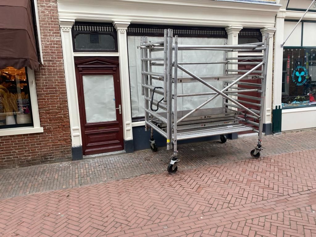 Een steiger staat voor een gebouw op een bakstenen trottoir.