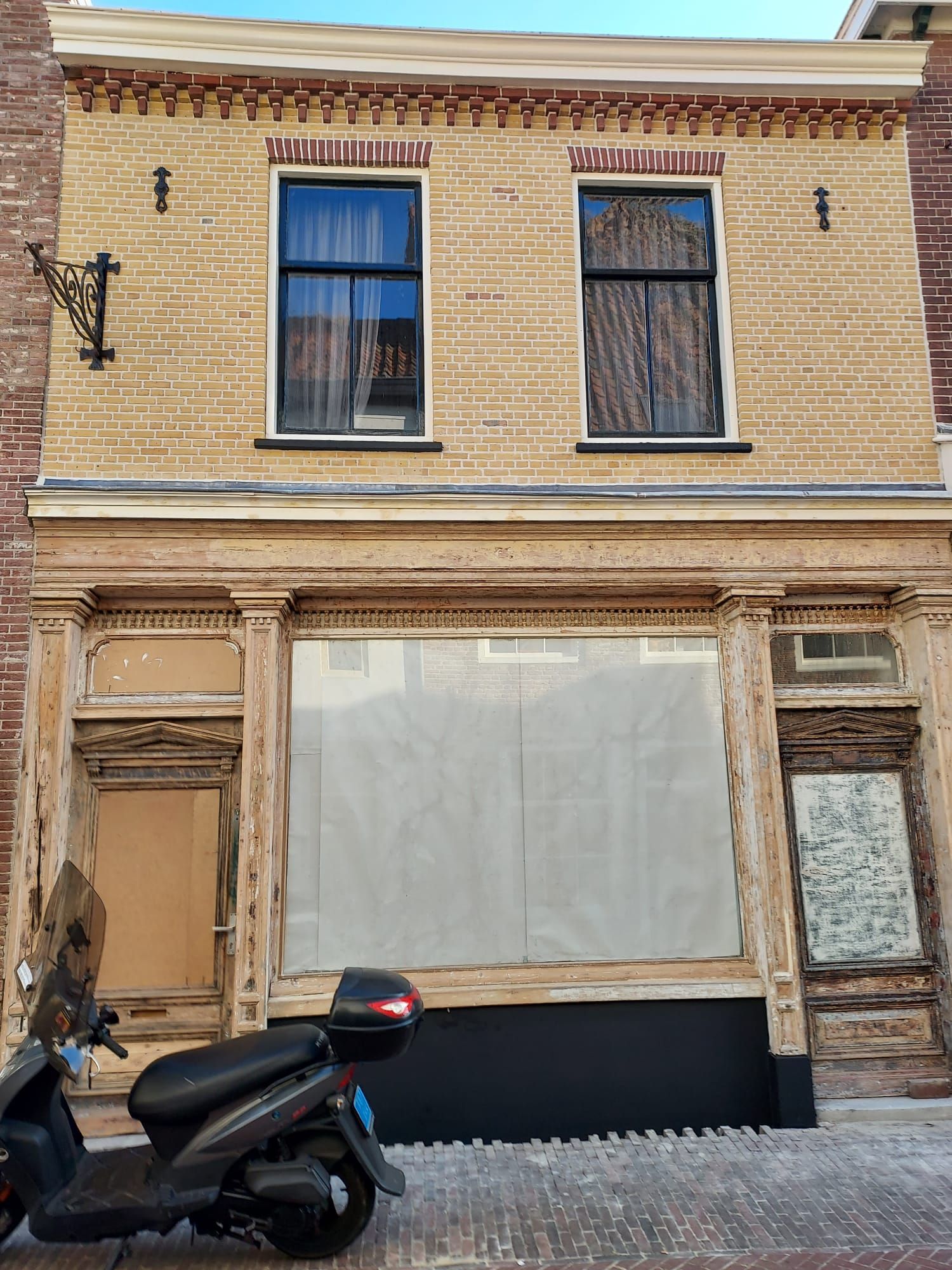 Voor een bakstenen gebouw staat een scooter geparkeerd