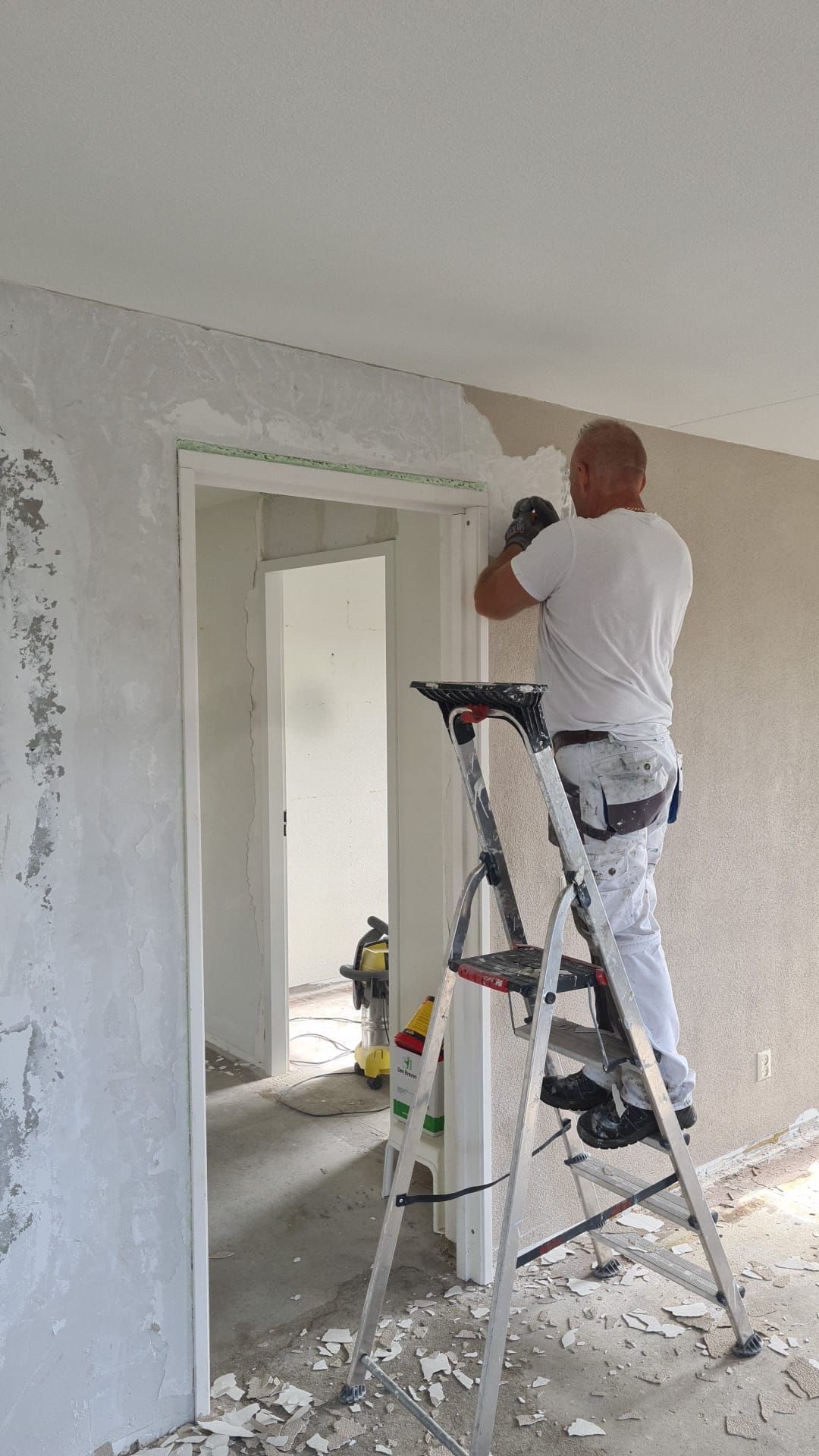 Een man staat op een ladder in een kamer.