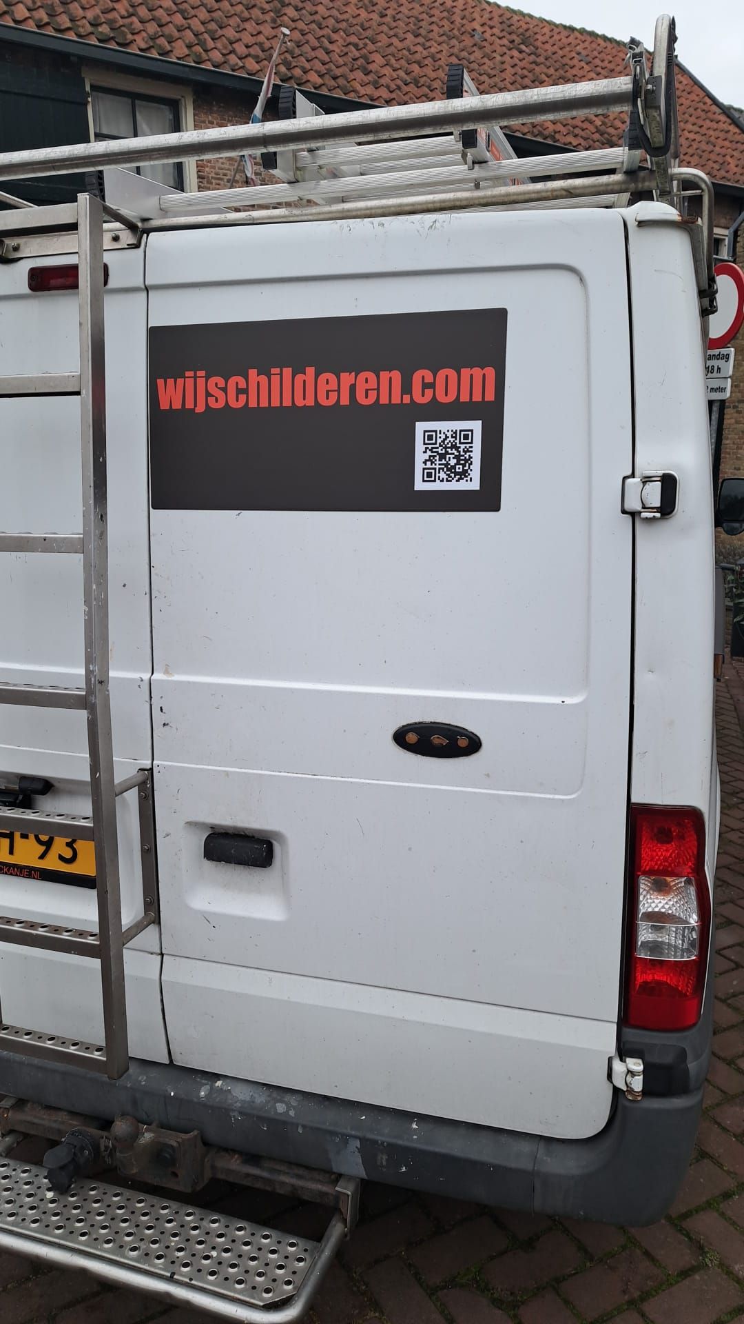 Een wit busje heeft een sticker op de achterkant met de tekst wijschilderen.com