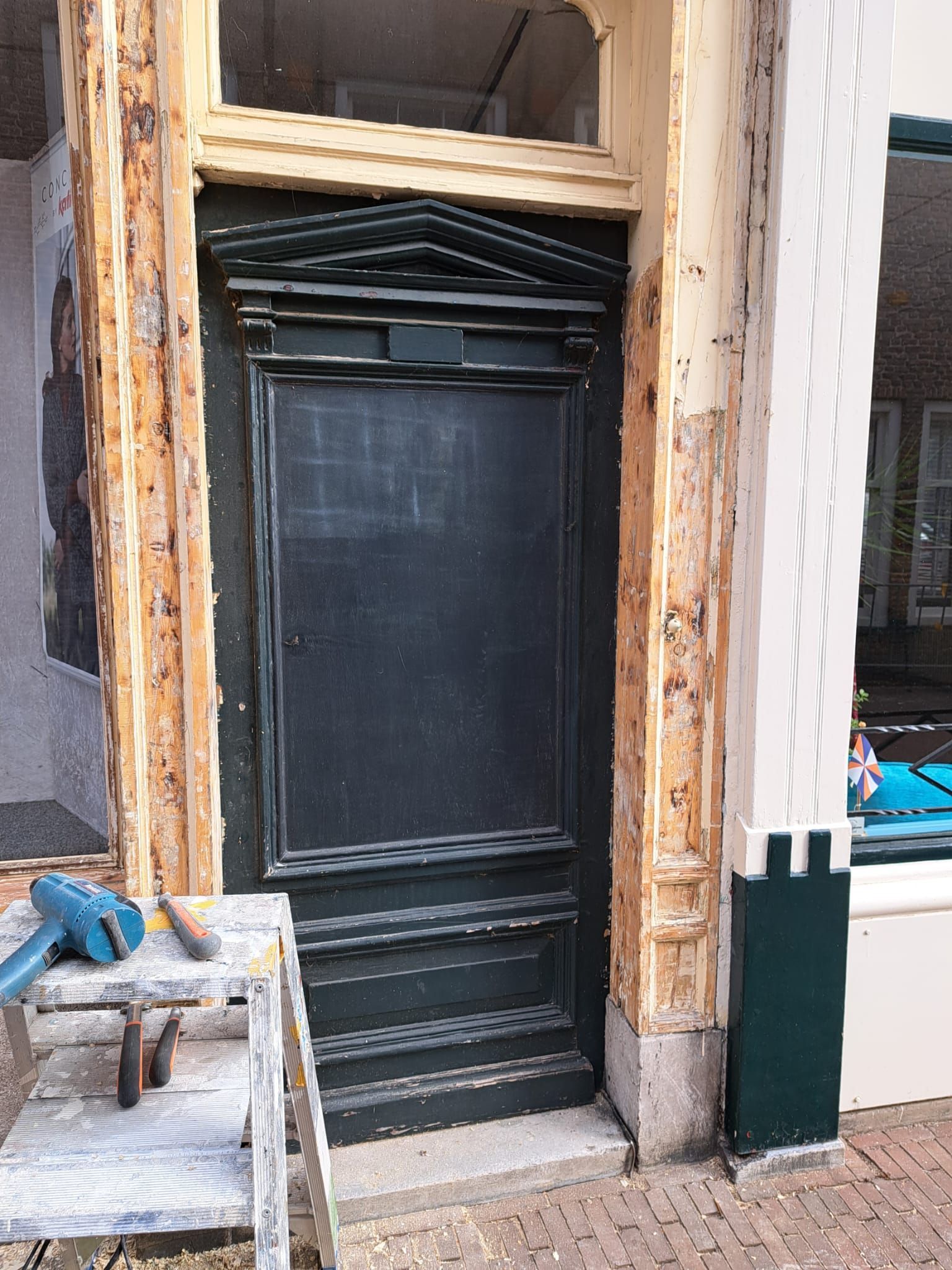 Aan de zijkant van een gebouw wordt een zwarte deur geschilderd.