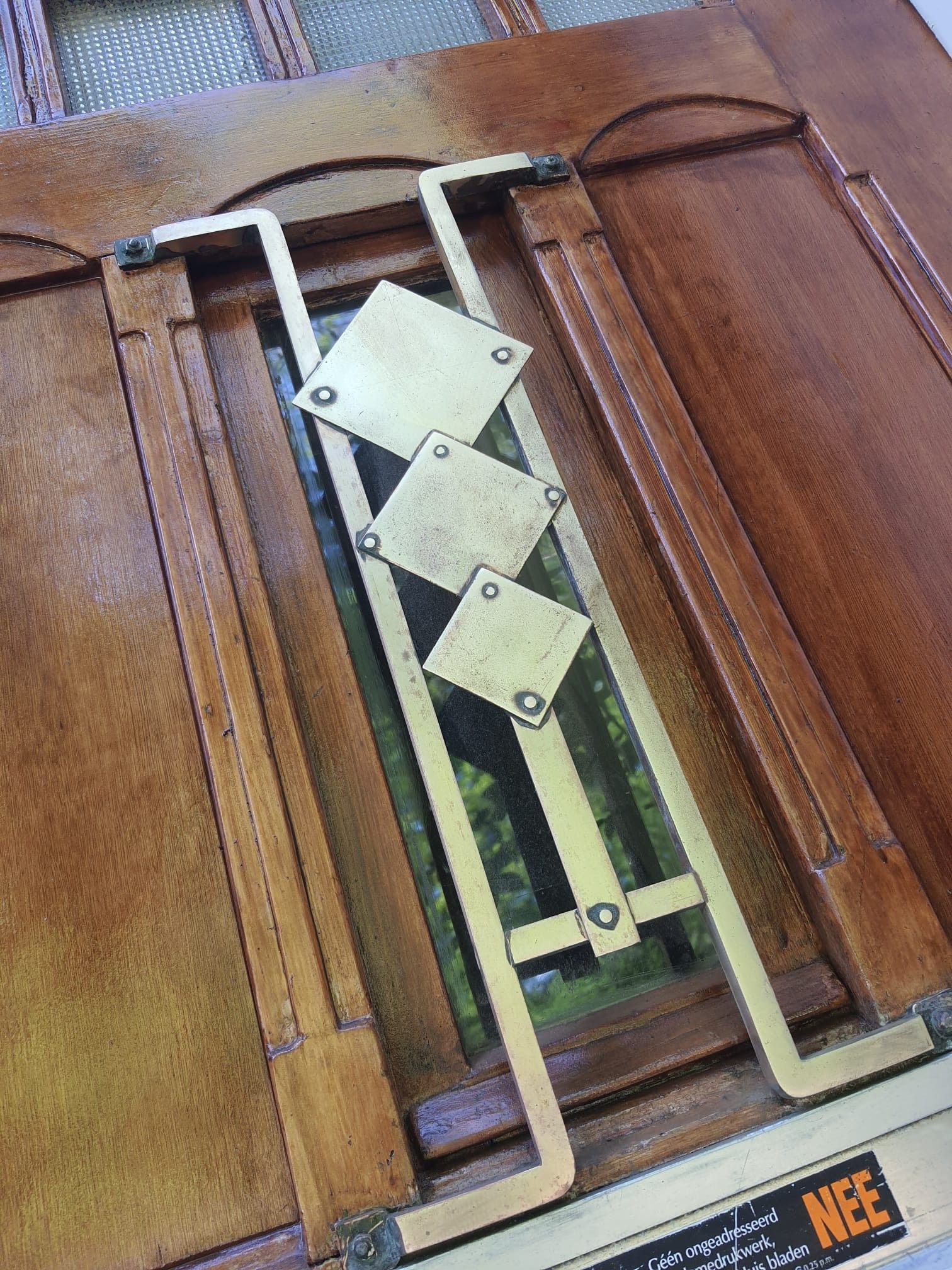 Een close-up van een houten deur met een koperen ontwerp erop.