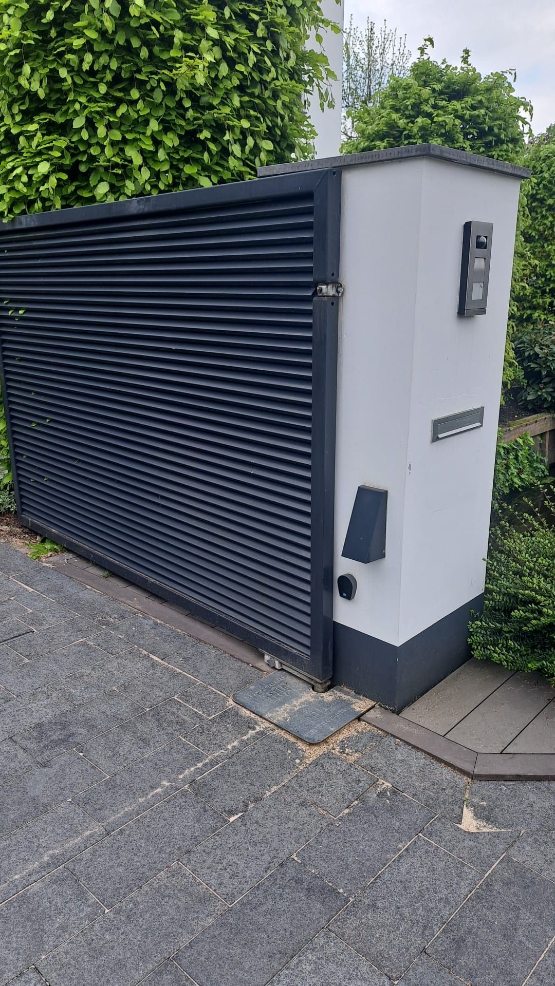 Een zwart-wit hek met aan de zijkant een brievenbus.