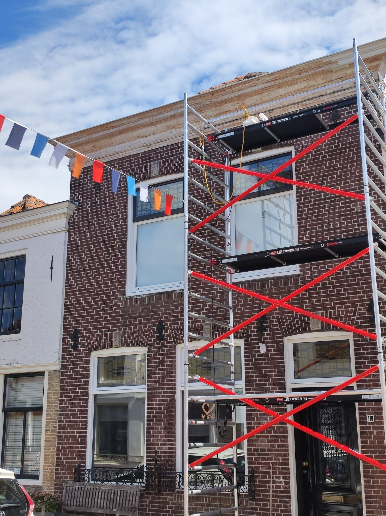 Voor een bakstenen gebouw staat een steiger.