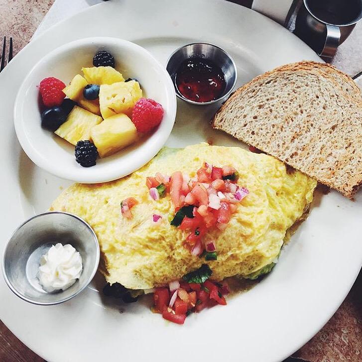 A plate of food with a bowl of fruit and a slice of bread