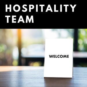 A welcome sign is sitting on a wooden table.