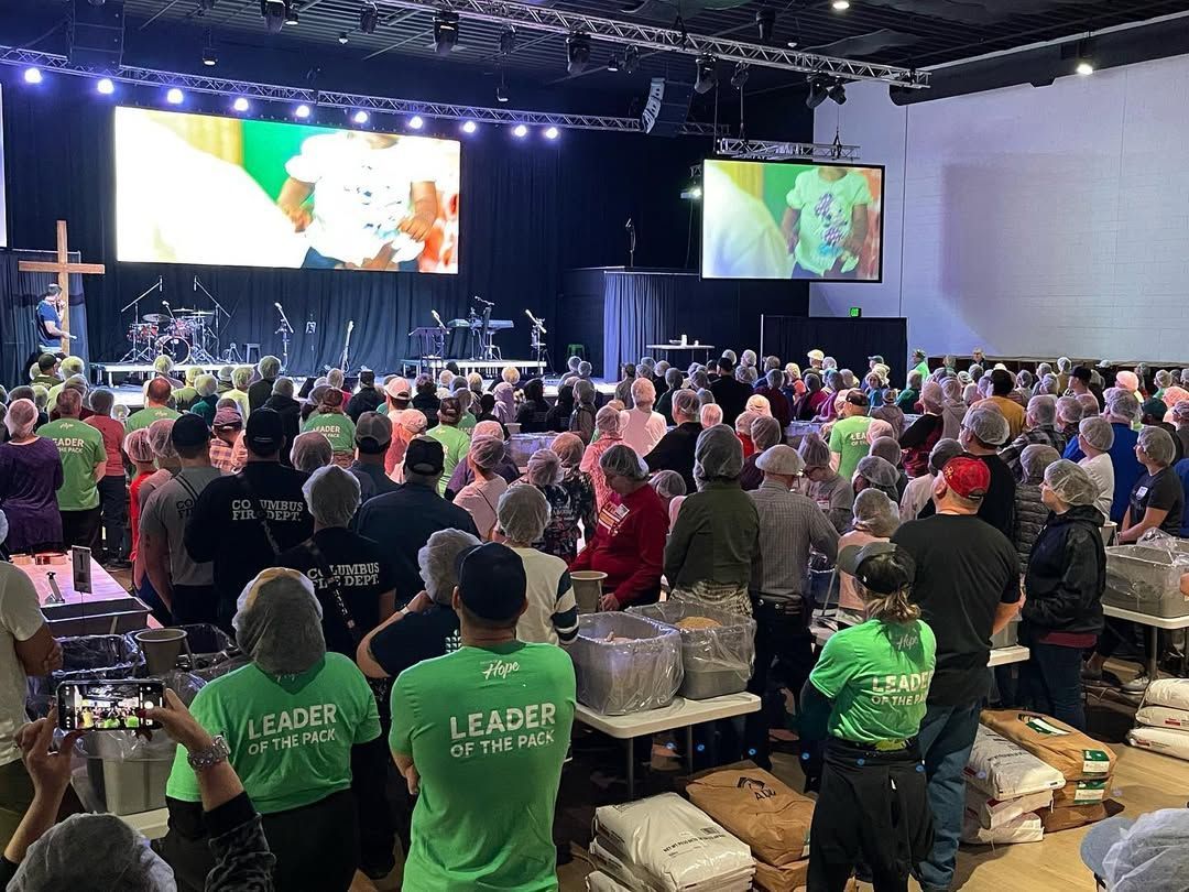 A large group of people are standing in a room watching a concert.