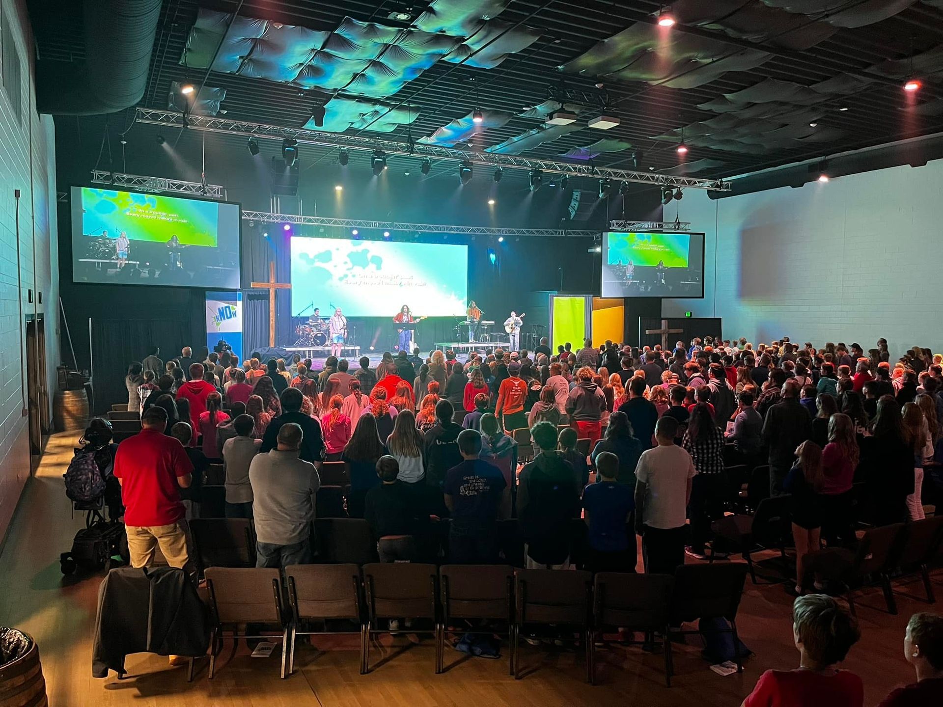 A large crowd of people are sitting in a large auditorium watching a concert.