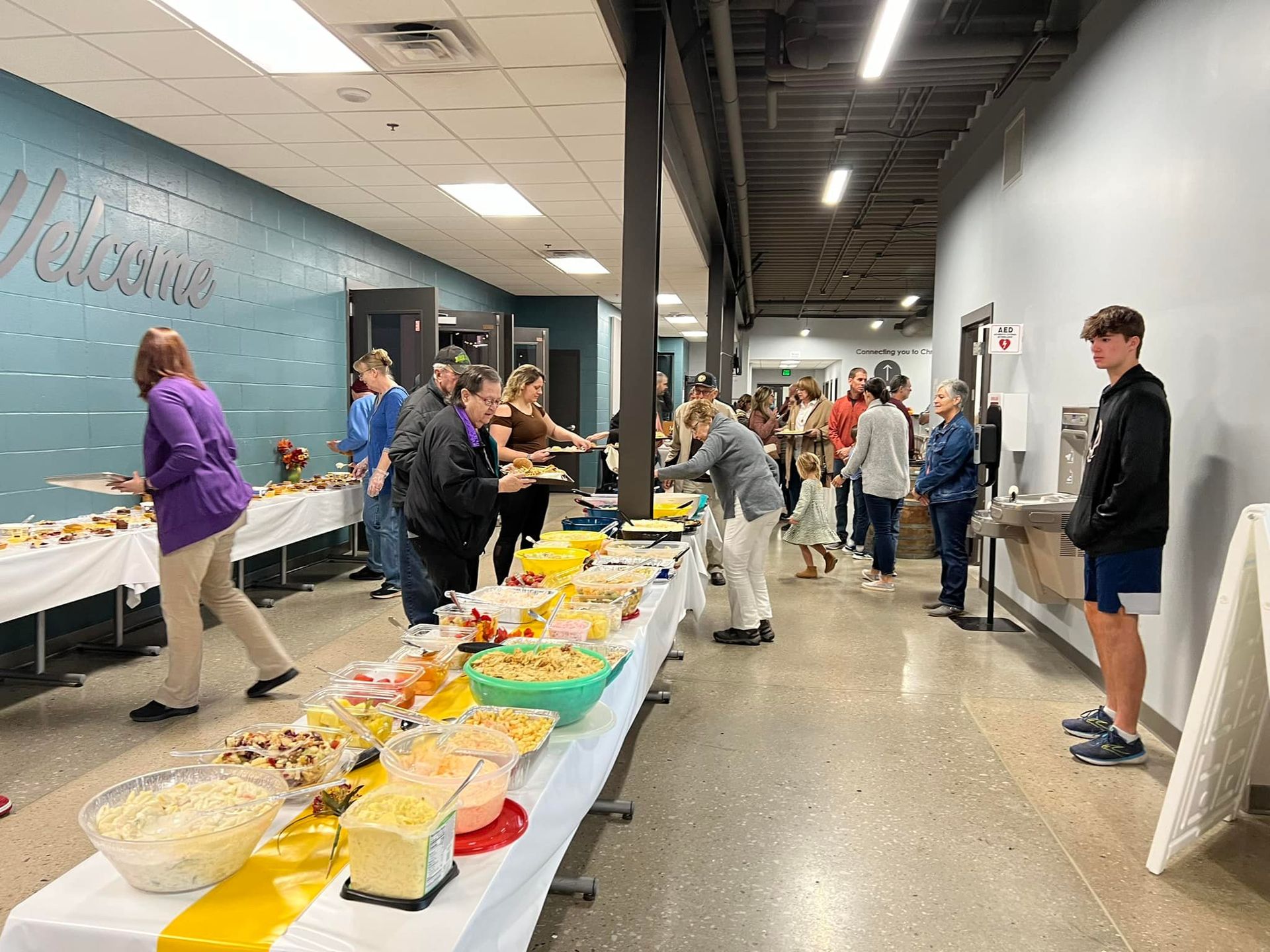 A group of people are standing around tables filled with food.