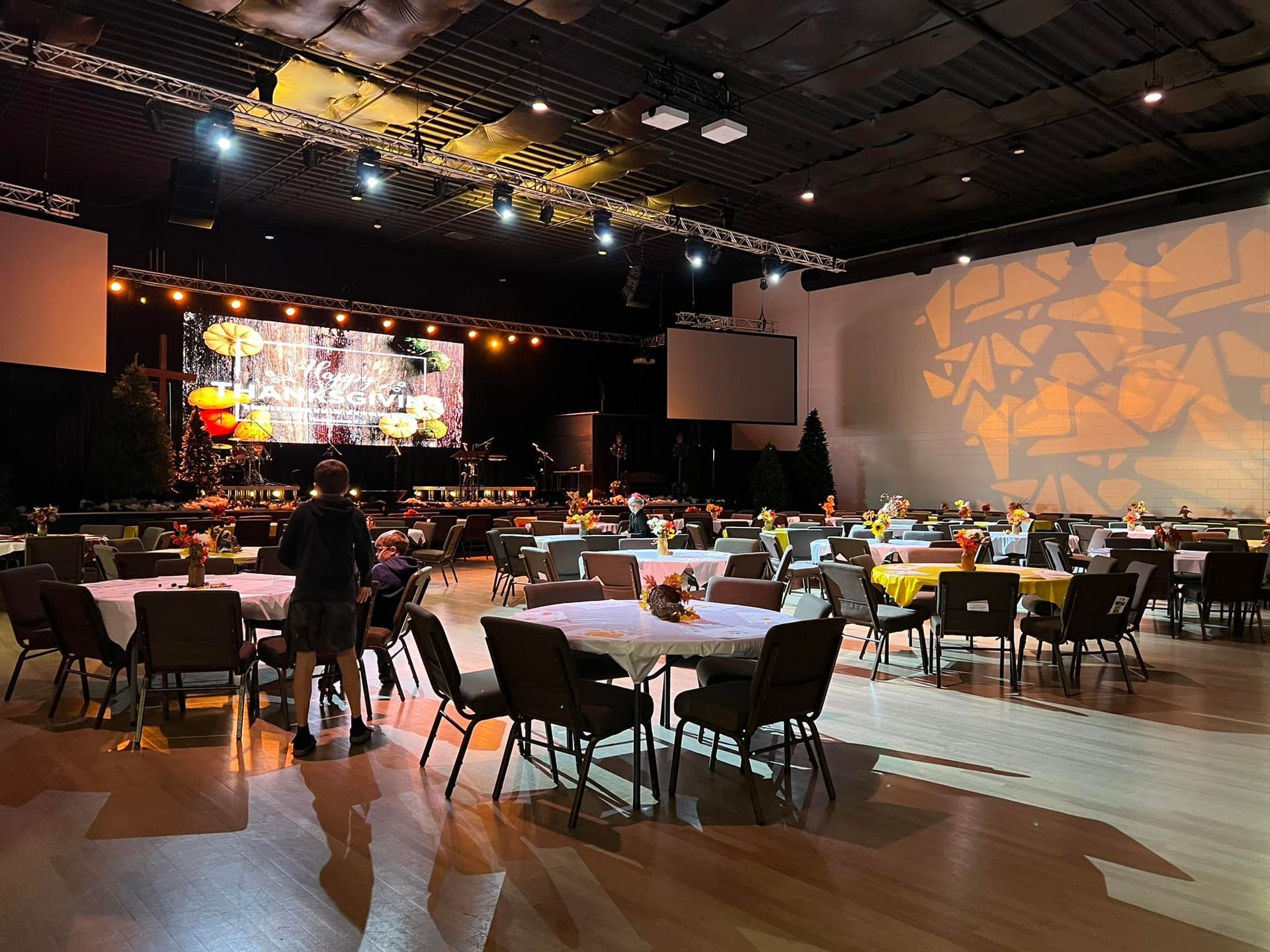 A large room filled with tables and chairs and a large screen.