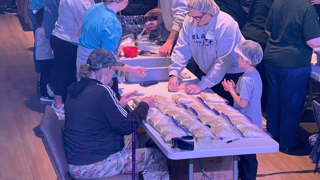A group of people are standing around a table.