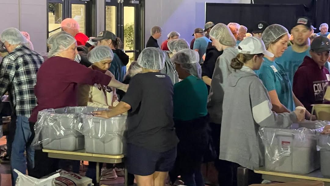 A group of people are standing around a table in a room.