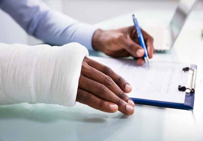 worker with a broken arm signing paper work