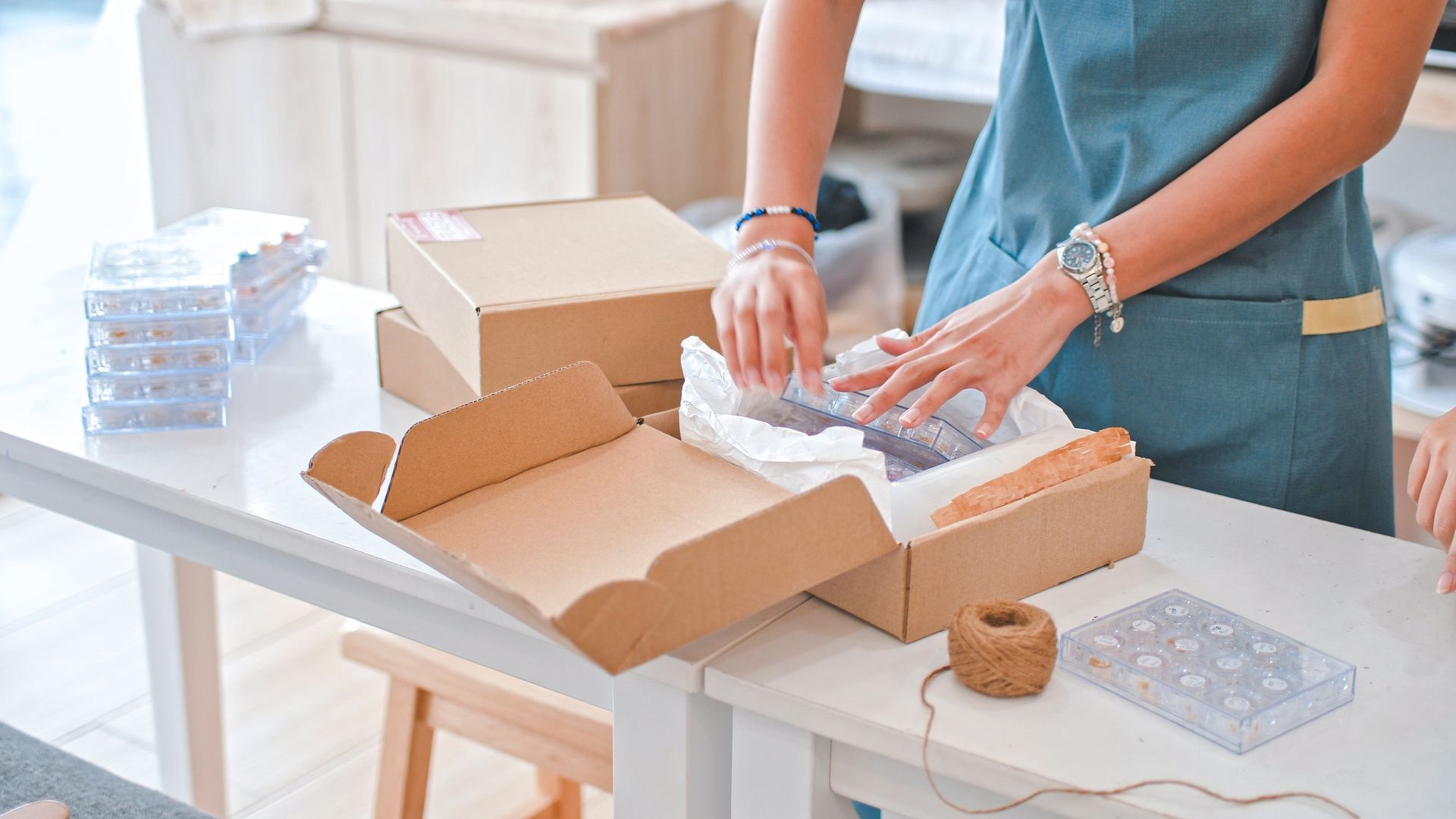 A woman is packing a box on a table.
