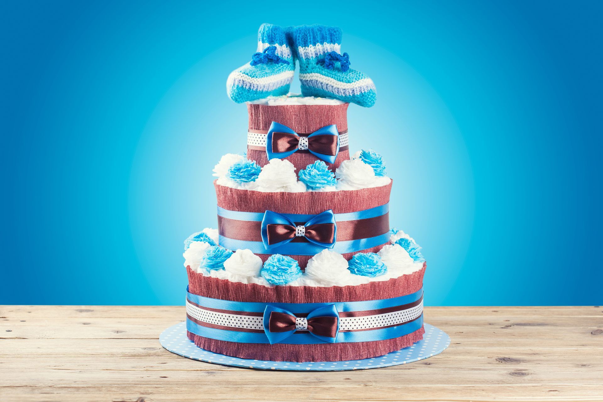 A diaper cake for a baby boy is sitting on a wooden table.