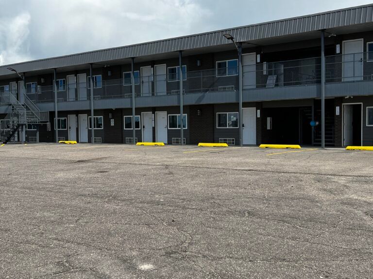 A motel with a parking lot in front of it.