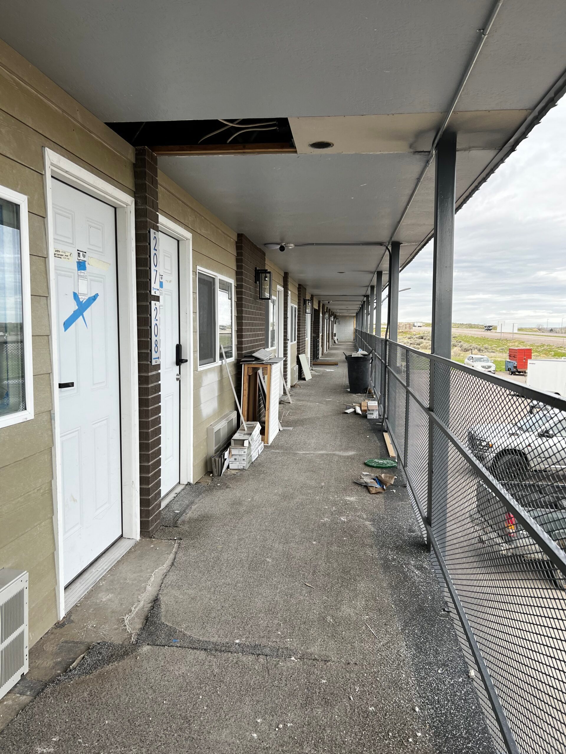 A long hallway between two buildings with a fence in the background.