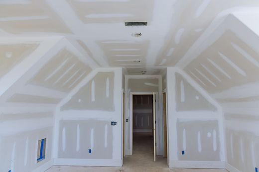 An empty room with a vaulted ceiling and drywall.