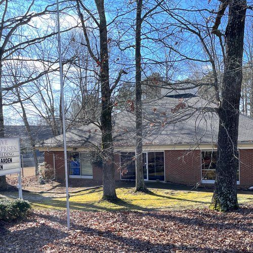 A brick house surrounded by trees and leaves on a sunny day.