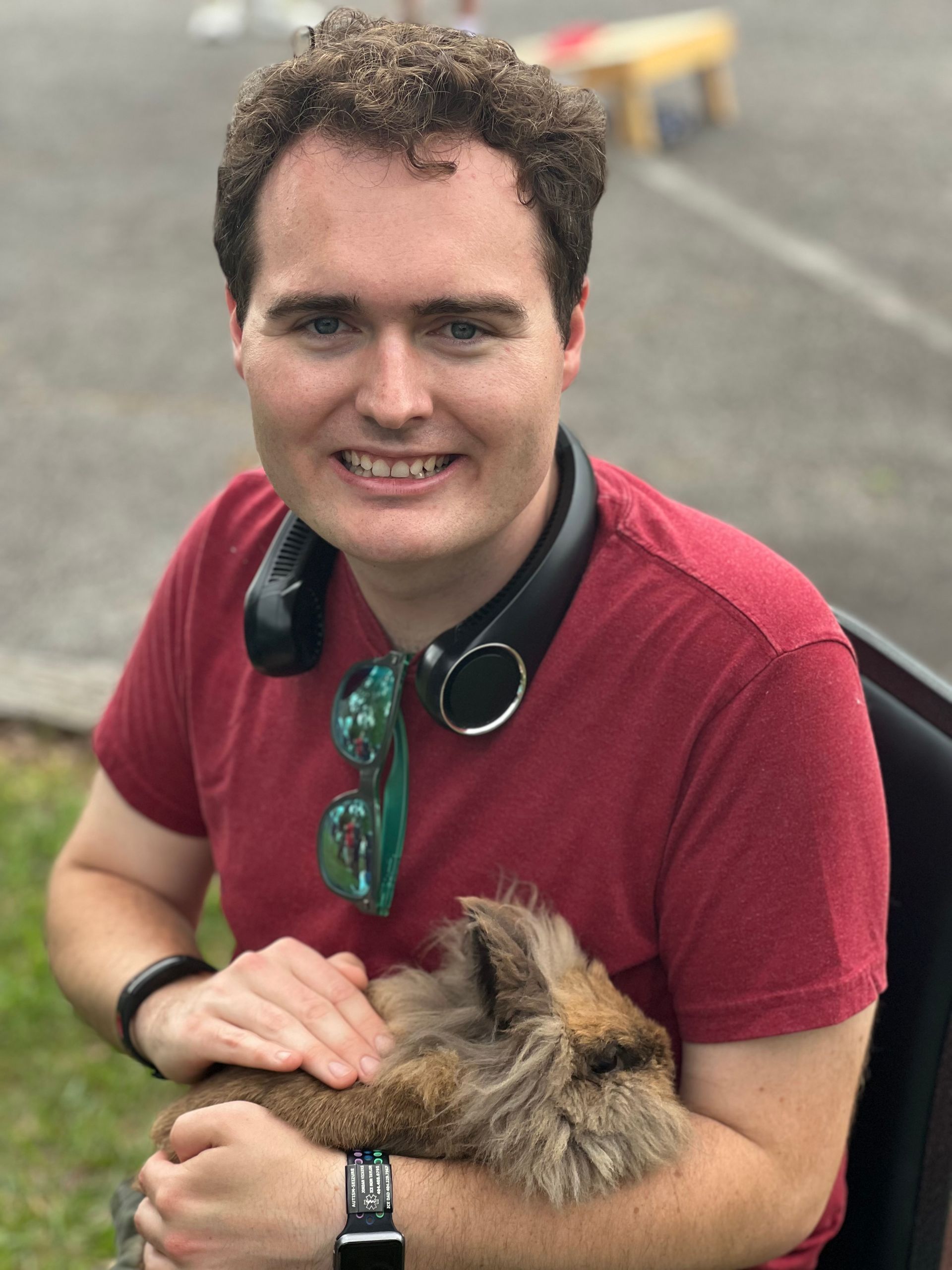 A man in a red shirt is holding a small dog