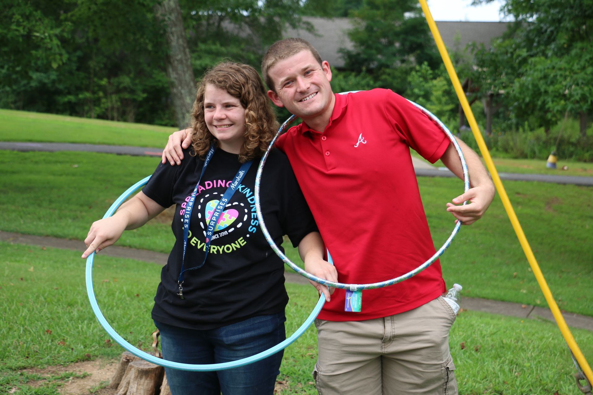 A man and a woman holding hula hoops in a park