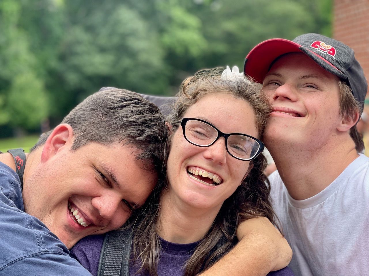 Two men and a woman are hugging each other and smiling for the camera.