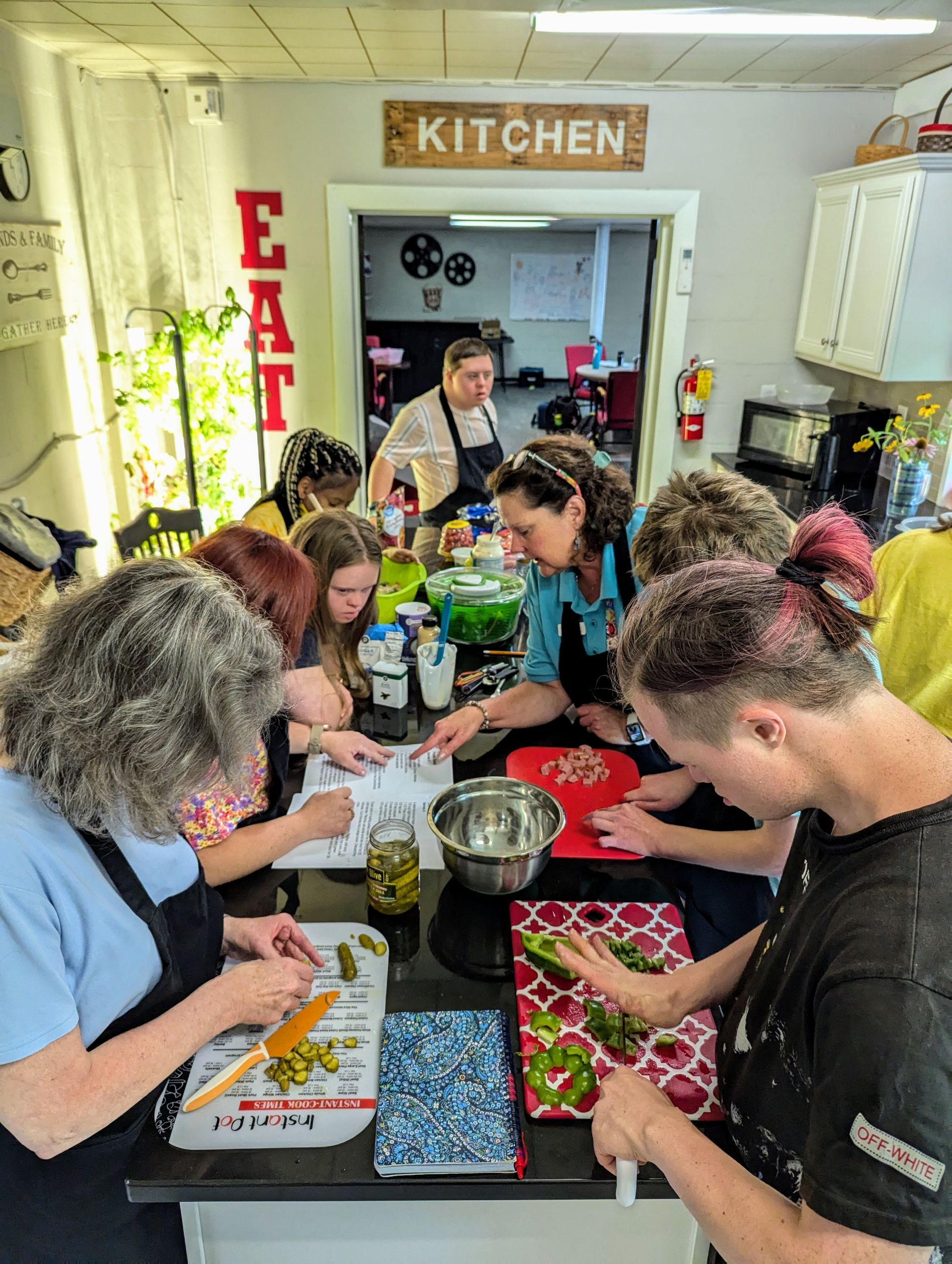 A group of people are sitting around a table in a kitchen preparing food.