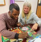 A man and a woman are sitting at a table playing a puzzle.