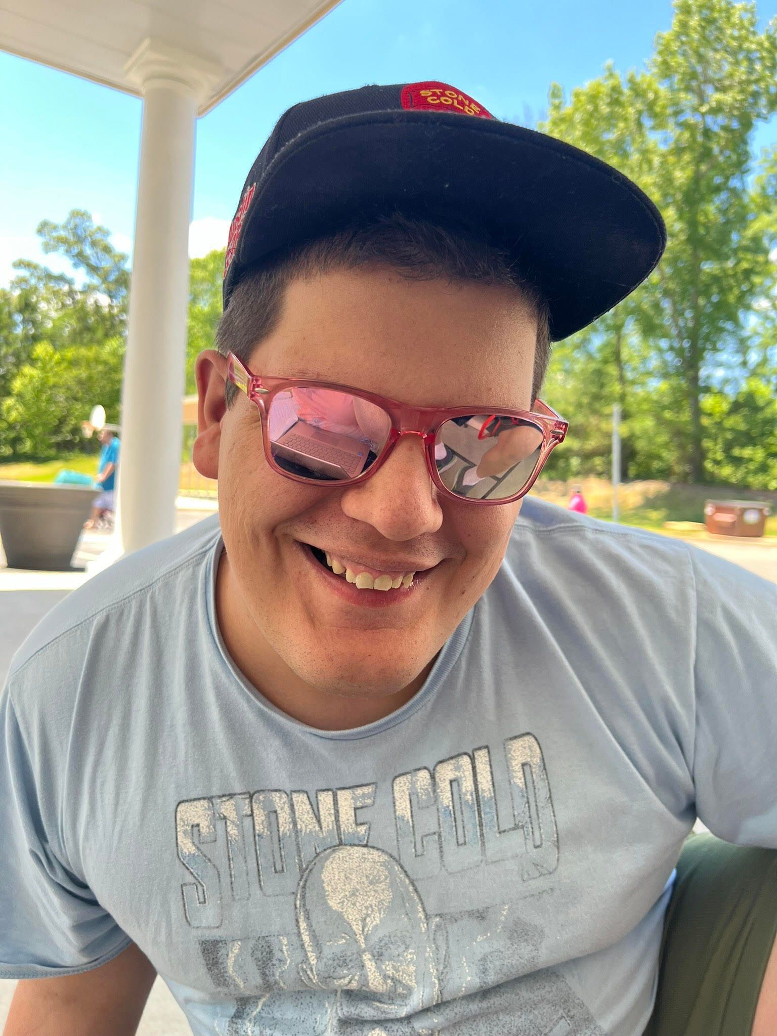 A man wearing sunglasses and a hat is smiling for the camera.