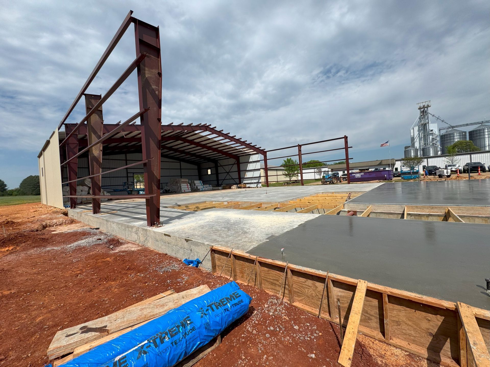 A blue pipe is laying on the ground in front of a building under construction.