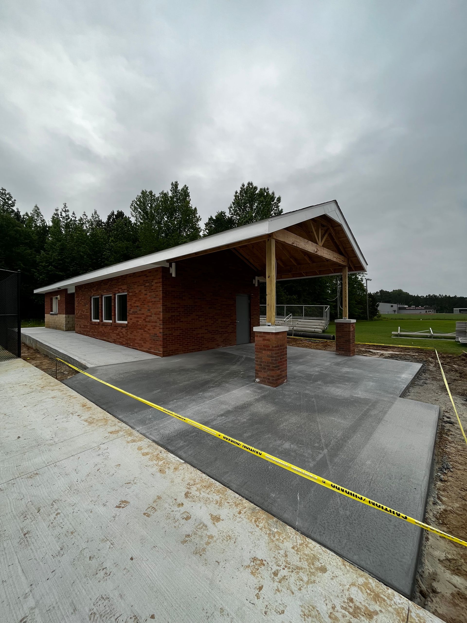 A brick building is being built next to a concrete driveway.
