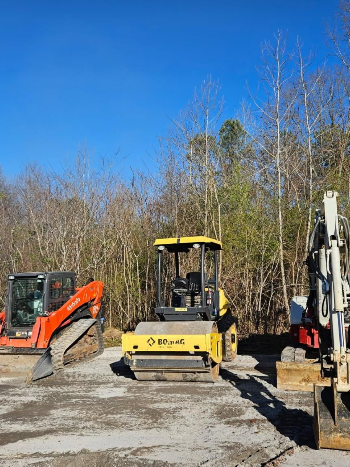 A group of construction vehicles are parked in a lot.